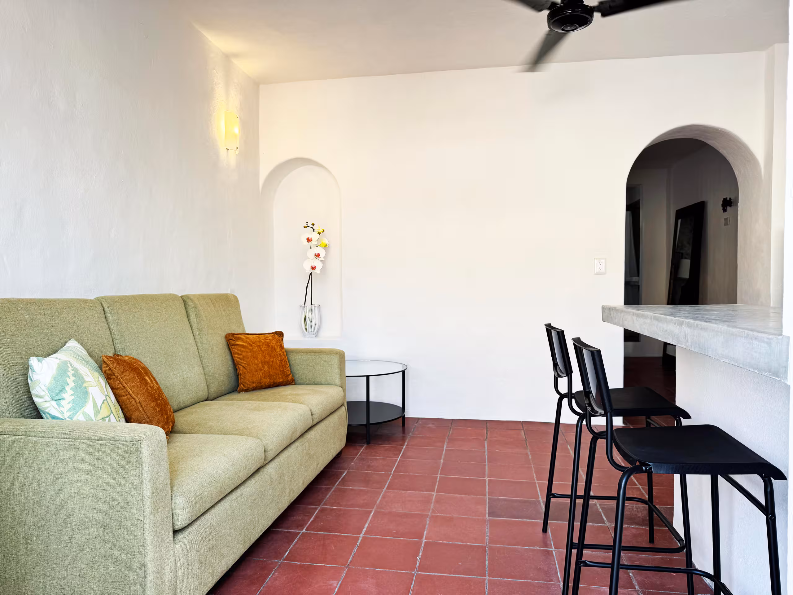 Green sofa, dining table and arched doorway